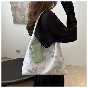 Detail view of the floral butterfly tote bag worn by a model in a minimalist room