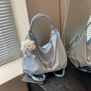 Light blue pleated tote bag with butterfly chain and cloud charm on wooden desk