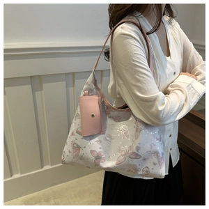 Détail du sac cabas à imprimé papillon avec un mini porte-monnaie rose sur la bandoulière