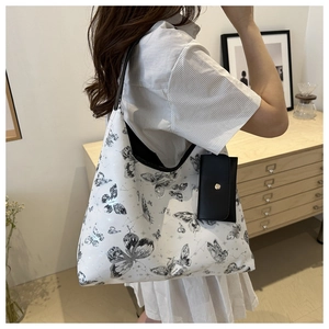 Détail du sac cabas blanc à imprimé papillon avec une petite pochette noire