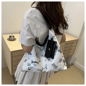 Detail of white tote bag with black butterfly print and detachable small pouch