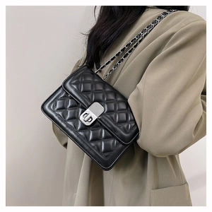 Detail showing black quilted leather texture and silver metal chain strap on shoulder bag