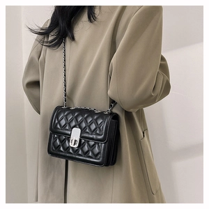 Detail of black quilted leather shoulder bag with silver turn-lock and chain strap