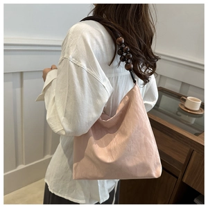 Detail of nude pink shoulder bag with natural texture fabric and dark wooden bead strap