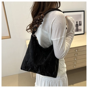 Detailed view of black pleated fabric and dark brown wooden bead shoulder strap on bag