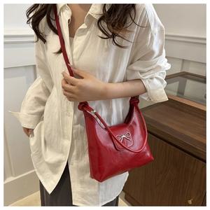 Gros plan d'un sac à bandoulière en cuir verni rouge avec un nœud en métal argenté