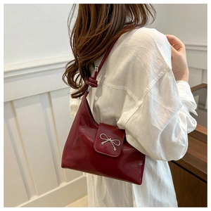 Detail of burgundy leather shoulder bag with silver bow buckle and knot strap detail