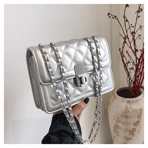 Close-up of silver quilted chain bag with metallic finish and rotary lock detail