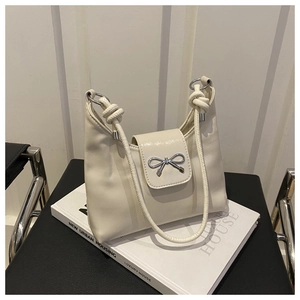 Détail du sac en cuir crème avec boucle nœud argentée et bandoulière nouée