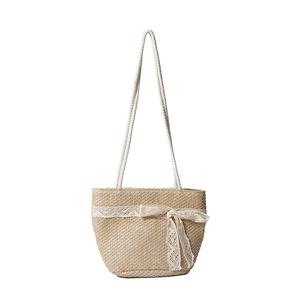 Straw shoulder bag with white lace trim and bow on natural woven material for summer beach