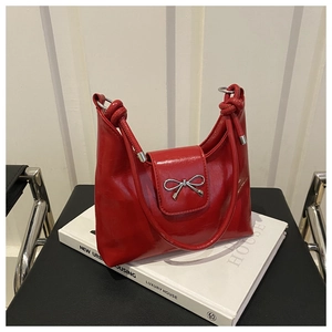 Détail du sac en cuir verni rouge avec nœud argenté et anse en corde nouée