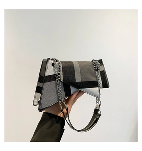 Detail view of the asymmetric geometric flap and silver metal chain on the checkered bag