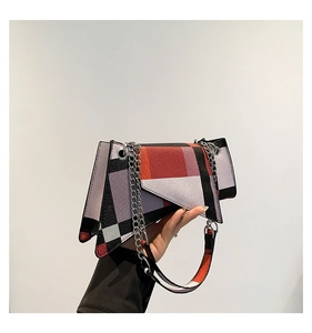 Detail of trendy color-block crossbody bag with geometric patchwork and silver chain strap