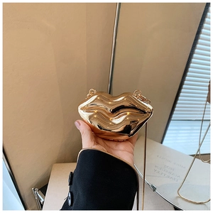 Detail showing a golden metallic lip-shaped mini clutch with a fine chain strap