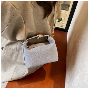 Detail of blue and white striped canvas crossbody bag with gold metal clasp closure