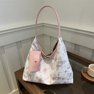 White tote bag with pink butterfly prints and matching small pouch on a wooden surface