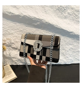 Détail du sac à chaîne en tissu écossais avec boucle en cristal et bandoulière en métal argenté