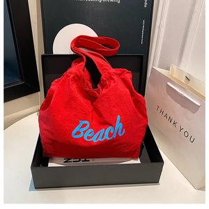 Détail du grand sac cabas rouge en toile avec lettrage Beach bleu dans une boîte cadeau