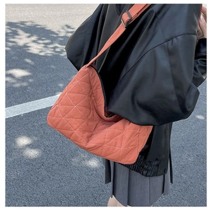 Close-up of orange quilted crossbody bag with geometric stitching and wide shoulder strap