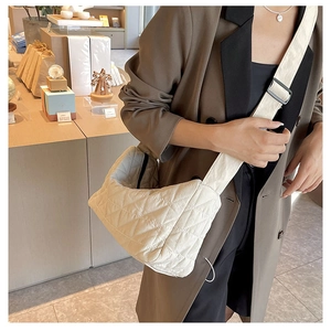 White quilted dumpling bag shown on model in a stylish interior boutique setting