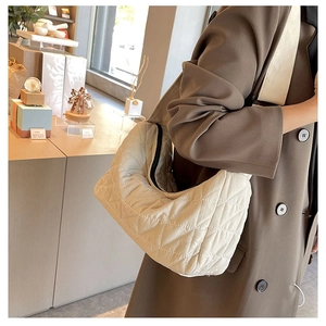 Detail view of cream quilted hobo bag with diamond pattern and black zipper closure
