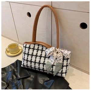 Detail of checkered tweed tote bag with brown leather handles and decorative silk scarf