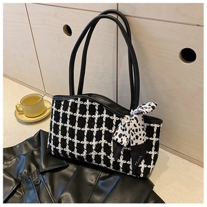 Detail view of black and white plaid tote bag with silk scarf on a stylish background