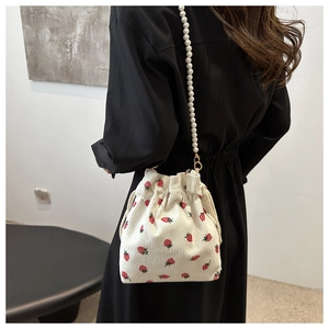 Sac seau en velours côtelé fraise avec bandoulière perle porté par un mannequin