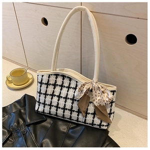Detail of tweed check tote bag with leopard print ribbon bow on a wooden surface