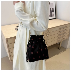 Détail du sac seau en velours côtelé noir avec broderie fraise et bandoulière perle