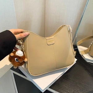 Beige faux leather underarm bag with decorative stitching and plush bear charm