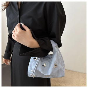 Gros plan d'un sac plissé bleu clair avec papillons argentés sur une robe noire