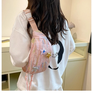 Detailed view of pink crossbody bag with star patches and adjustable strap on a model