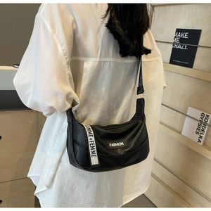 Detail of black litchi grain crescent crossbody bag with adjustable strap and text webbing