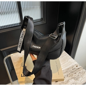 Detail view of black lychee grain leather tote with Fashion label and canvas strap