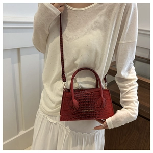 Detail view of red crocodile pattern leather handbag with fashion metal lettering