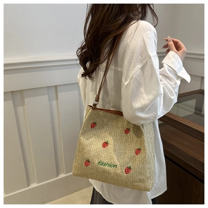 Détail de la broderie fraise et du texte fashion sur le sac seau en paille tissée