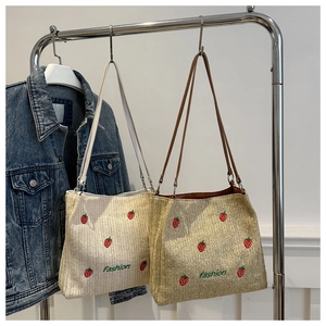 Détail du cabas en paille avec broderie de fraises colorées et texte de mode stylé