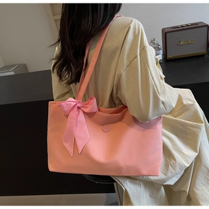 Back view of pink canvas tote bag with a bow knot and E-logo emblem on a model