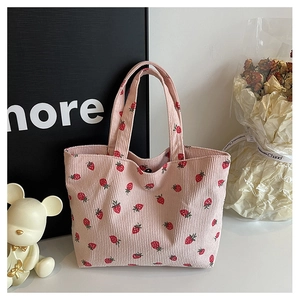 Détail d'un sac cabas en velours côtelé rose avec motifs de fraises et texture douce