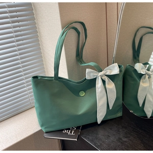Detail of dark green tote bag with plaid bow ornament and letter E decorative button