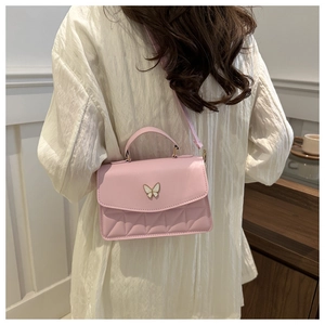 Detail of pink PU leather crossbody bag featuring quilted stitching and butterfly hardware