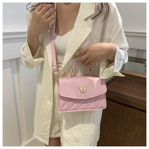Pink quilted crossbody bag with butterfly clasp shown on a person in a white suit