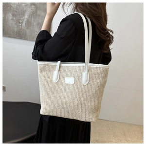 Détail d'un sac cabas en paille tressée avec bordures et fines bandoulières en cuir blanc
