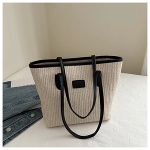 Détail du sac fourre-tout en paille tressée avec bordure en cuir noir sur denim
