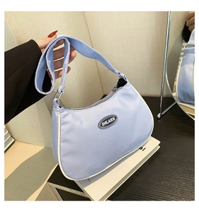 Close-up of light blue nylon crescent bag with brand logo and white contrast piping