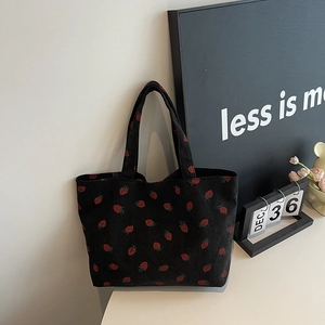Sac cabas chic en velours côtelé noir avec imprimé fraise dans un intérieur épuré