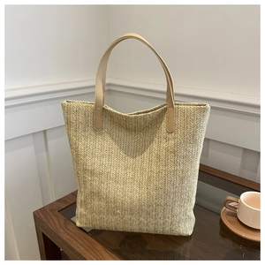 Close-up of the herringbone woven texture and faux leather straps on the straw tote bag