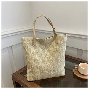 Detail of woven tote bag showing beige V-pattern texture and soft leather handles