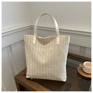 Detailed herringbone woven texture and leather handles on a beige summer tote bag